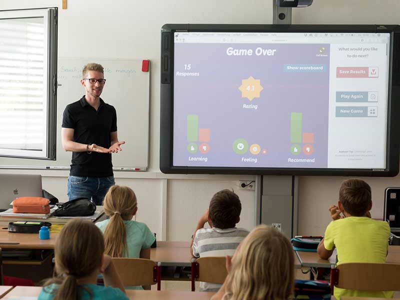 a teacher standing in front of a class of elementary schoolers