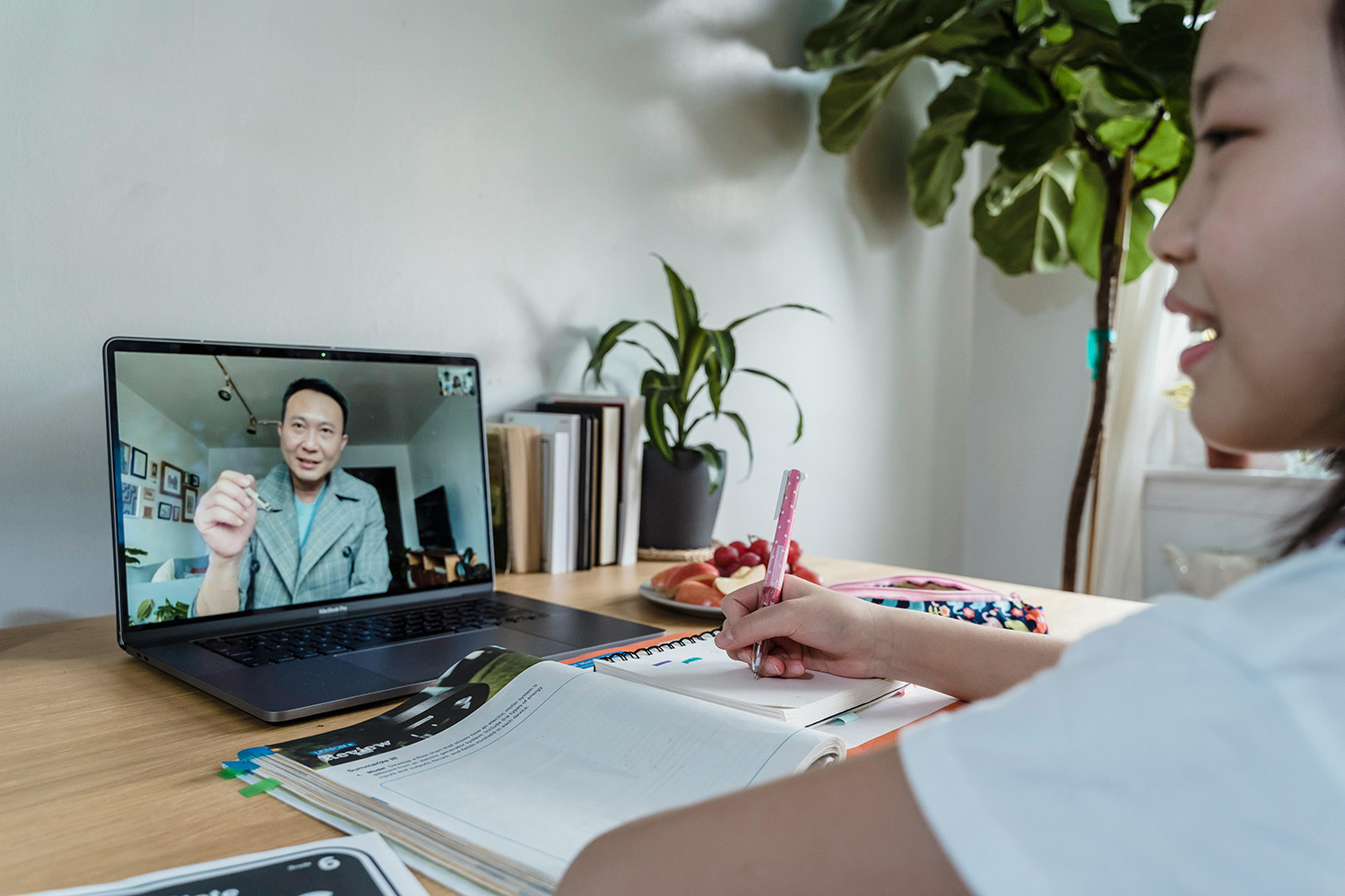 a student sits in front of a computer monitor with a man's face on the screen