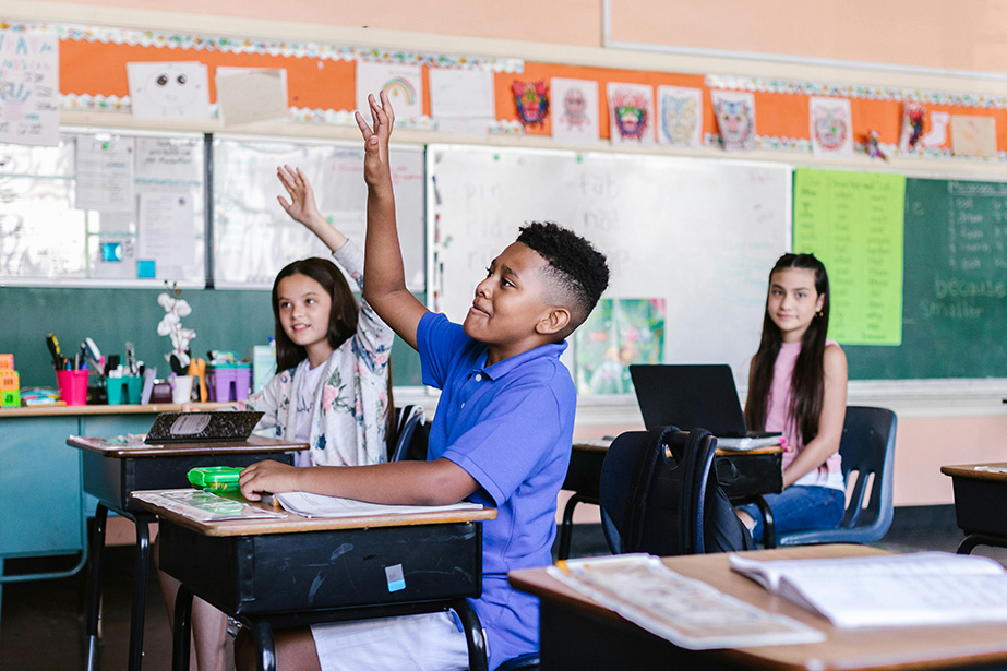 Students in a classroom raising their hands